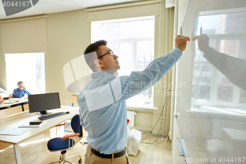 Image of students and teacher writing on school white board