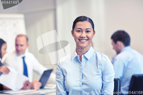 Image of group of smiling businesspeople meeting in office