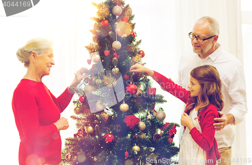 Image of smiling family decorating christmas tree at home