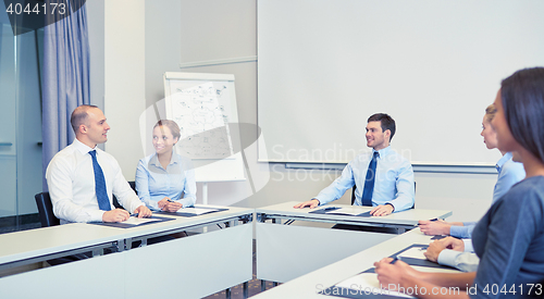 Image of group of smiling businesspeople meeting in office