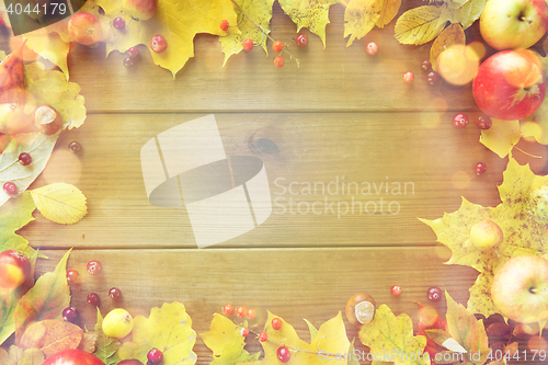 Image of frame of autumn leaves, fruits and berries on wood