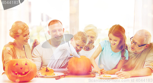 Image of happy family sitting with pumpkins at home