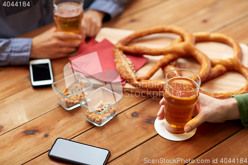 Image of close up of hands with smartphones and beer at bar