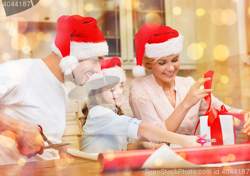 Image of smiling family in santa helper hats with gift box