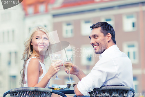 Image of smiling couple drinking wine in cafe