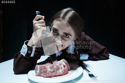 Image of Bloody Halloween theme: crazy girl with a knife and meat