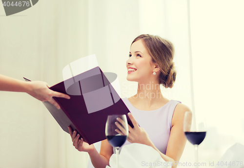 Image of smiling woman recieving menu from waiter