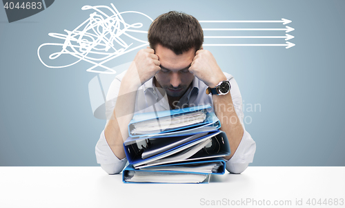 Image of sad businessman with stack of folders at office
