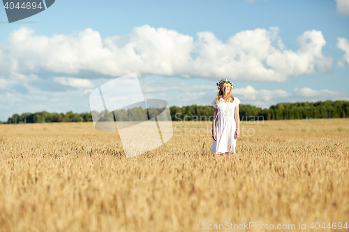 Image of happy young woman in flower wreath on cereal field