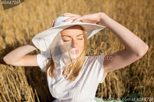 Image of happy young woman in sun hat on cereal field