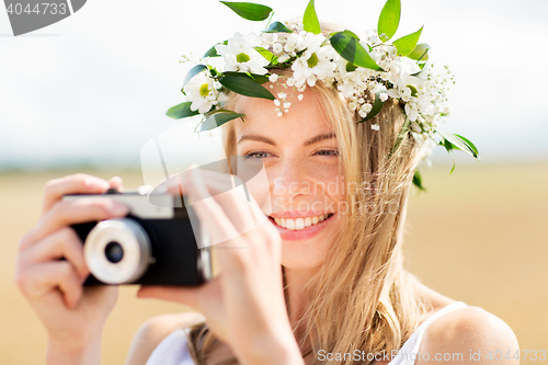 Image of happy woman with film camera in wreath of flowers