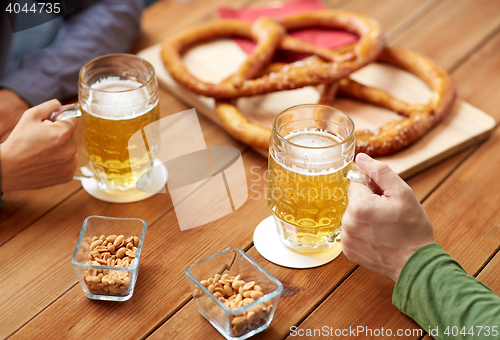 Image of close up of hands with beer mugs at bar or pub