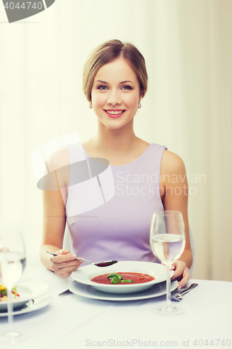 Image of smiling young woman eating appetizer at restaurant