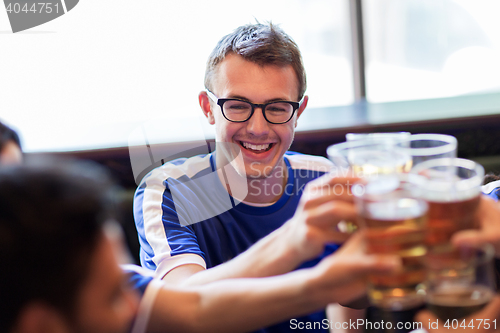 Image of football fans clinking beer glasses at sport bar