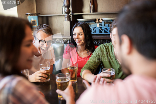 Image of happy friends drinking beer at bar or pub