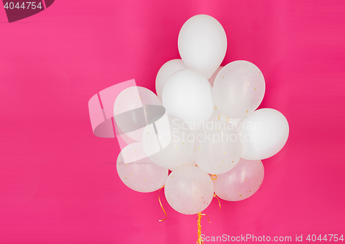 Image of close up of white helium balloons over pink