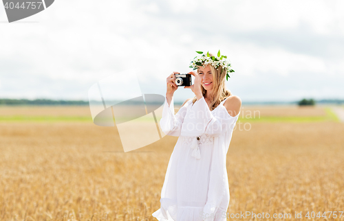 Image of happy woman with film camera in wreath of flowers