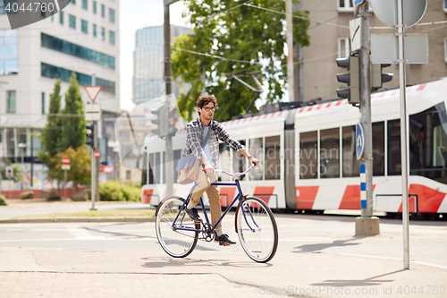 Image of young hipster man with bag riding fixed gear bike