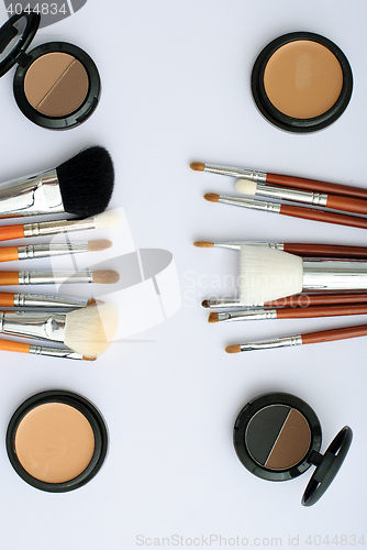 Image of makeup brush and cosmetics, on a white background