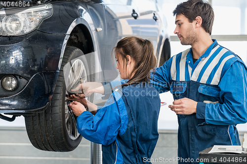 Image of Mechanics Changing Tire From Suspended Car At Garage