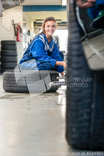 Image of Happy Female Mechanic Changing Car Tire At Automobile Shop