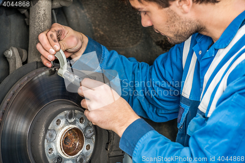 Image of Male Car Mechanic Examining Brake Disc With Caliper