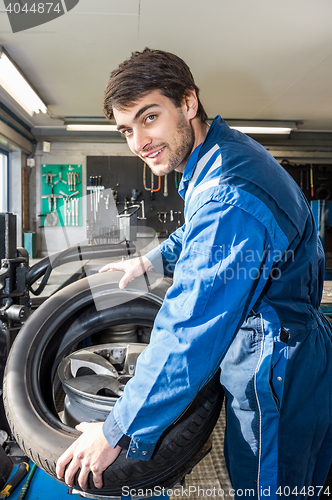 Image of Confident Mechanic Mounting Car Tire On Rim In Garage