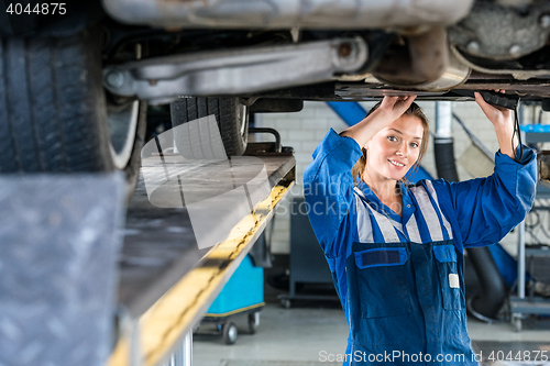 Image of Female Mechanic Working Under Car On Hydraulic Lift