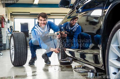 Image of Confident Mechanic Changing Car Tire In Garage