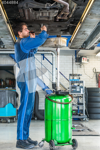 Image of Mechanic Repairing Car On Hydraulic Lift In Automobile Shop