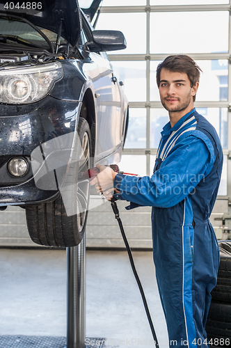 Image of Male Mechanic Using Pneumatic Wrench To Fix Car Tire