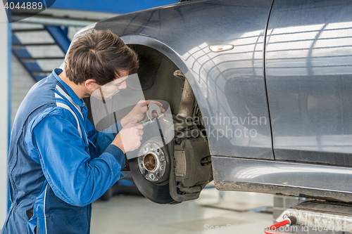 Image of Car Mechanic Examining Brake Disc With Caliper