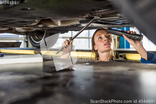 Image of Mechanic With Flashlight Repairing Car On Hydraulic Lift