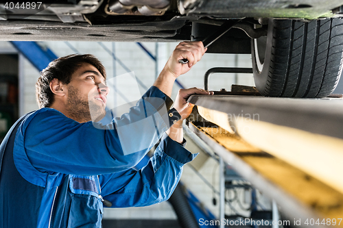 Image of Mechanic Changing Tire From Suspended Car At Automobile Shop