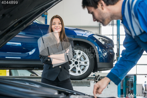 Image of Confident Businesswoman With Mechanic Repairing Her Car