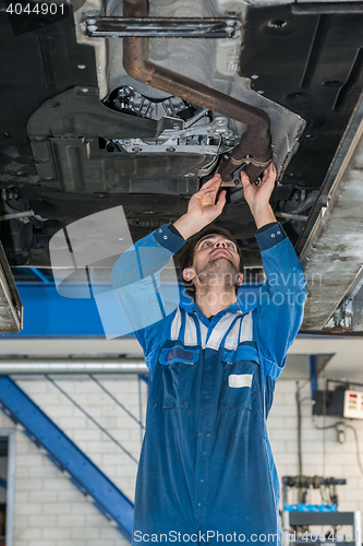 Image of Male Mechanic Examining Exhaust System Of Car