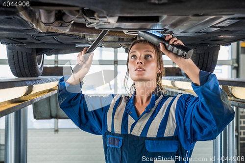 Image of Female Mechanic Using Flashlight While Repairing Car On Lift