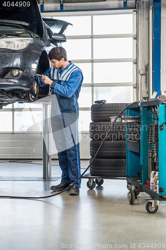 Image of Mechanic Repairing Brake Of Lifted Automobile At Garage