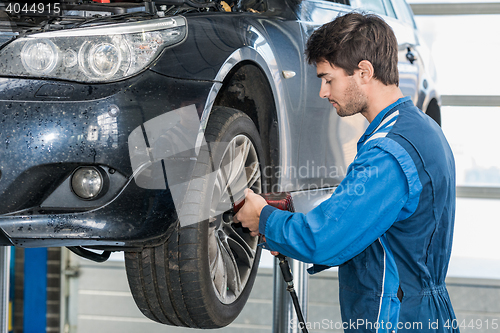 Image of Mechanic Using Pneumatic Wrench To Fix Car Tire