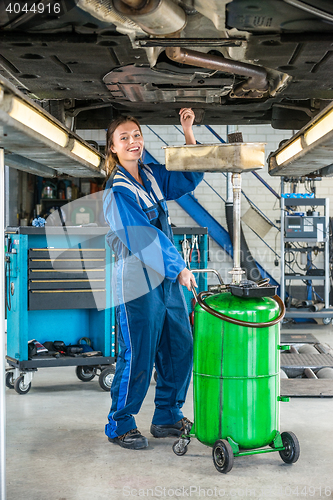 Image of Female Mechanic Repairing Car On Hydraulic Lift In Garage