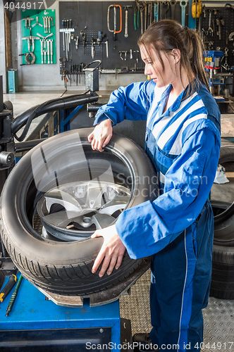 Image of Female Mechanic Mounting Car Tire On Rim In Garage
