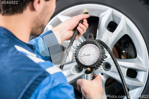 Image of Mechanic Checking Tire Pressure With Gauge