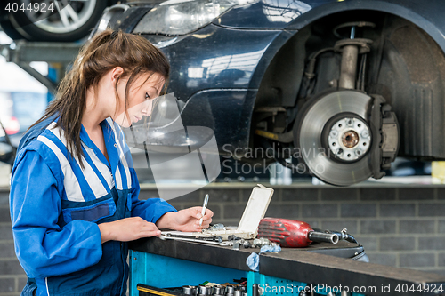 Image of Young Female Mechanic Making Notes In Garage