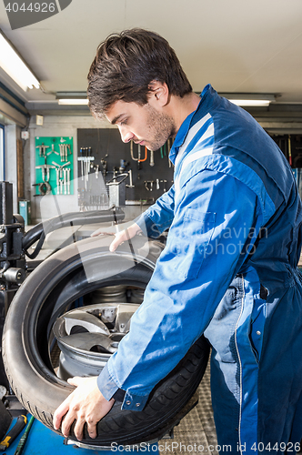 Image of Mechanic Mounting Car Tire On Alloy Rim In Garage