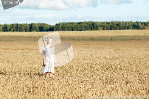 Image of happy young woman in flower wreath on cereal field