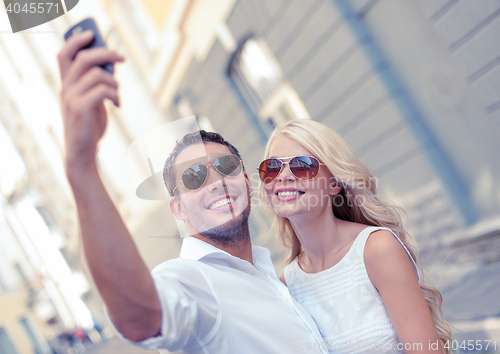 Image of smiling couple with smartphone in the city