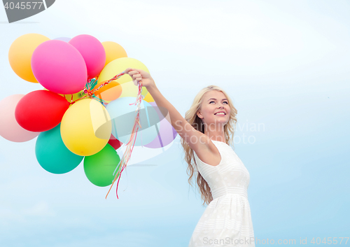 Image of smiling woman with colorful balloons outside