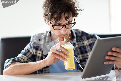 Image of man with tablet pc and earphones sitting at cafe