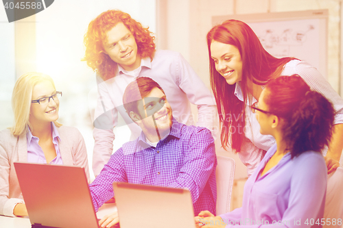 Image of smiling team with laptop computers in office