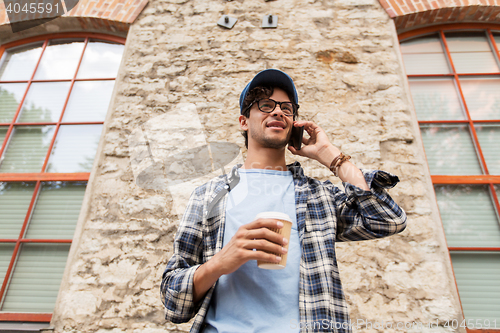 Image of man with smartphone drinking coffee on city street